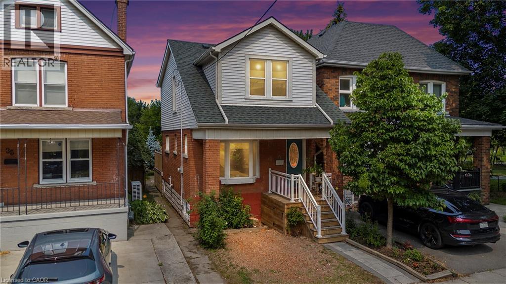 Brick facade home featuring a gabled roofline, front porch with white railings, and a paved driveway