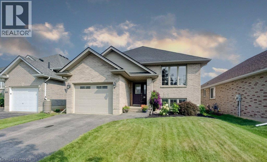 Light brick exterior featuring a single car driveway, attached garage with a panel door, established landscaping
