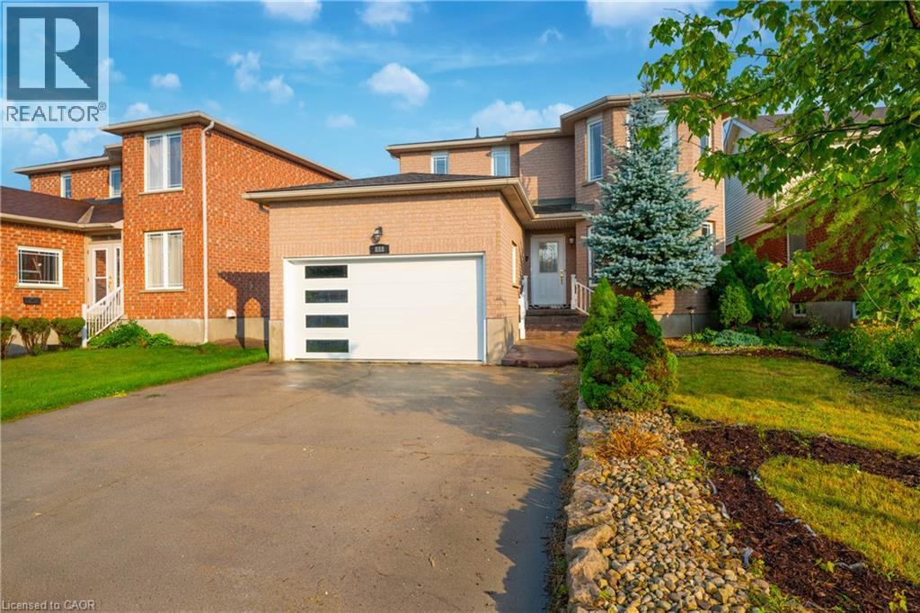 Brick exterior residence featuring a modern garage door with frosted panels, an asphalt driveway, and a stone-lined garden bed