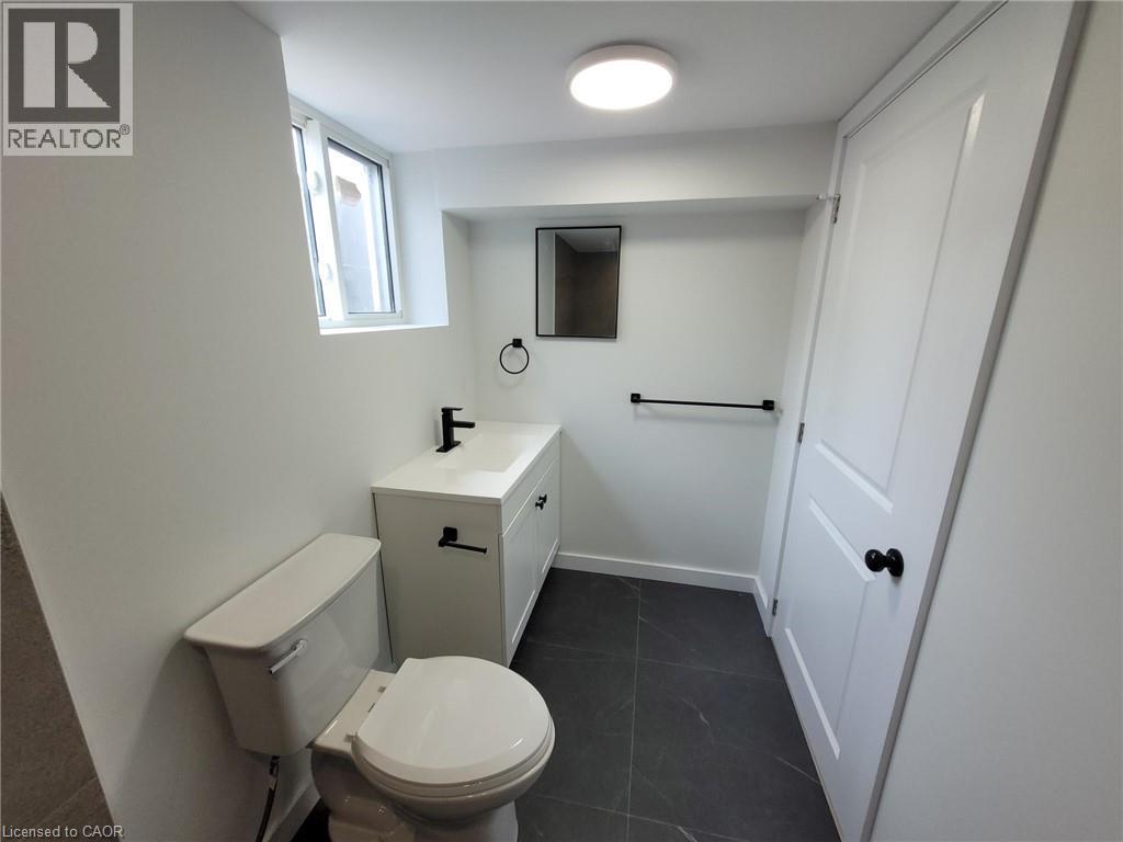 Bathroom featuring a white vanity with integrated sink, matte black fixtures, dark gray tile flooring, a white two-panel door, and a horizontal window