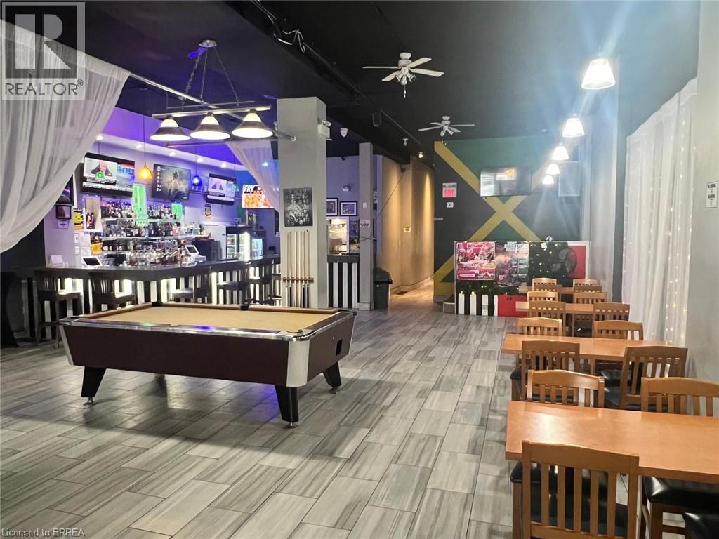 Open concept commercial space featuring a full-service bar with built-in shelving, recessed lighting, and ceiling fans