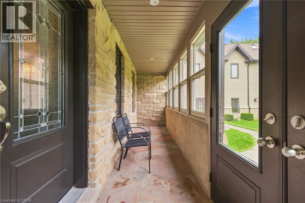 Covered porch with stone wall detailing, flagstone flooring, and multiple windows