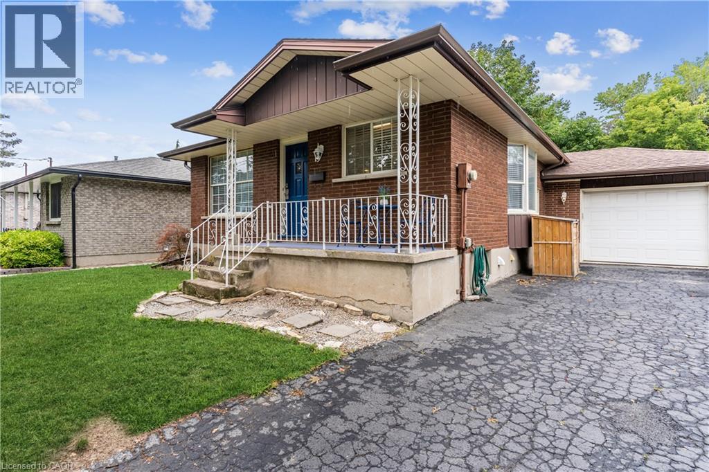 Brick exterior with covered front porch, decorative metal railings, and an attached single-car garage