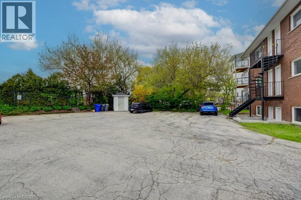 Exterior parking area featuring a paved surface, mature perimeter trees, and a storage shed