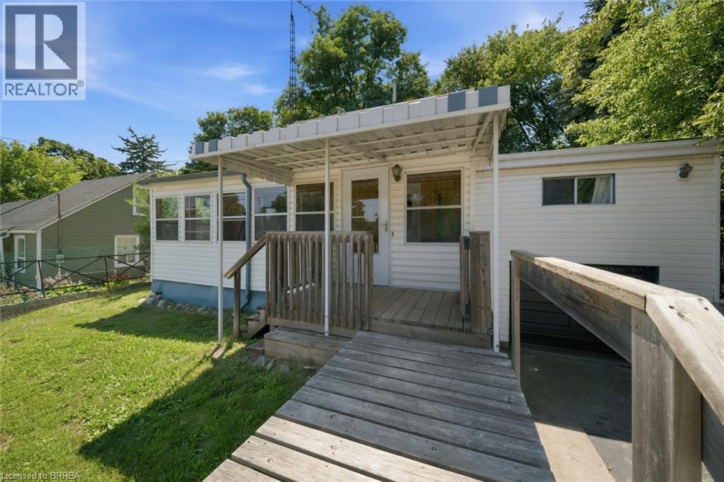 Exterior featuring white vinyl siding, a covered porch with an awning, and a wooden ramp