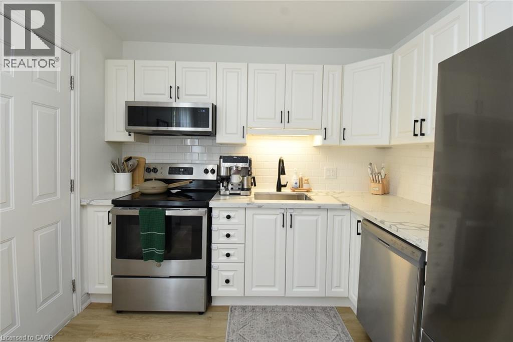 Contemporary kitchen featuring white cabinetry, stainless steel appliances, a subway tile backsplash, and light-toned countertops