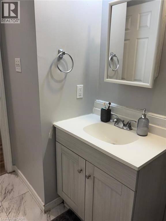 Bathroom vanity featuring a white countertop with an integrated sink, dual-door base cabinet, and chrome faucet