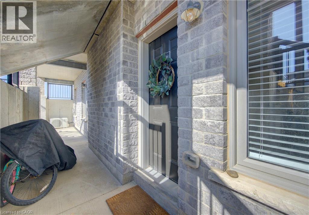 Exterior entry featuring light grey brick facade, dark entry door, and a window with horizontal blinds