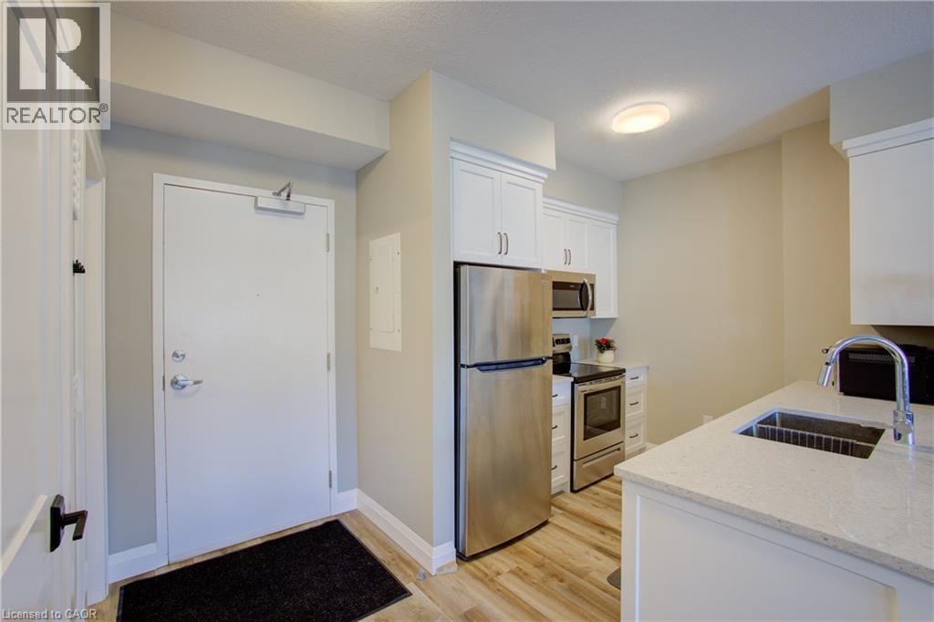 Kitchen with white shaker cabinetry, stainless steel appliances, and a light-toned countertop