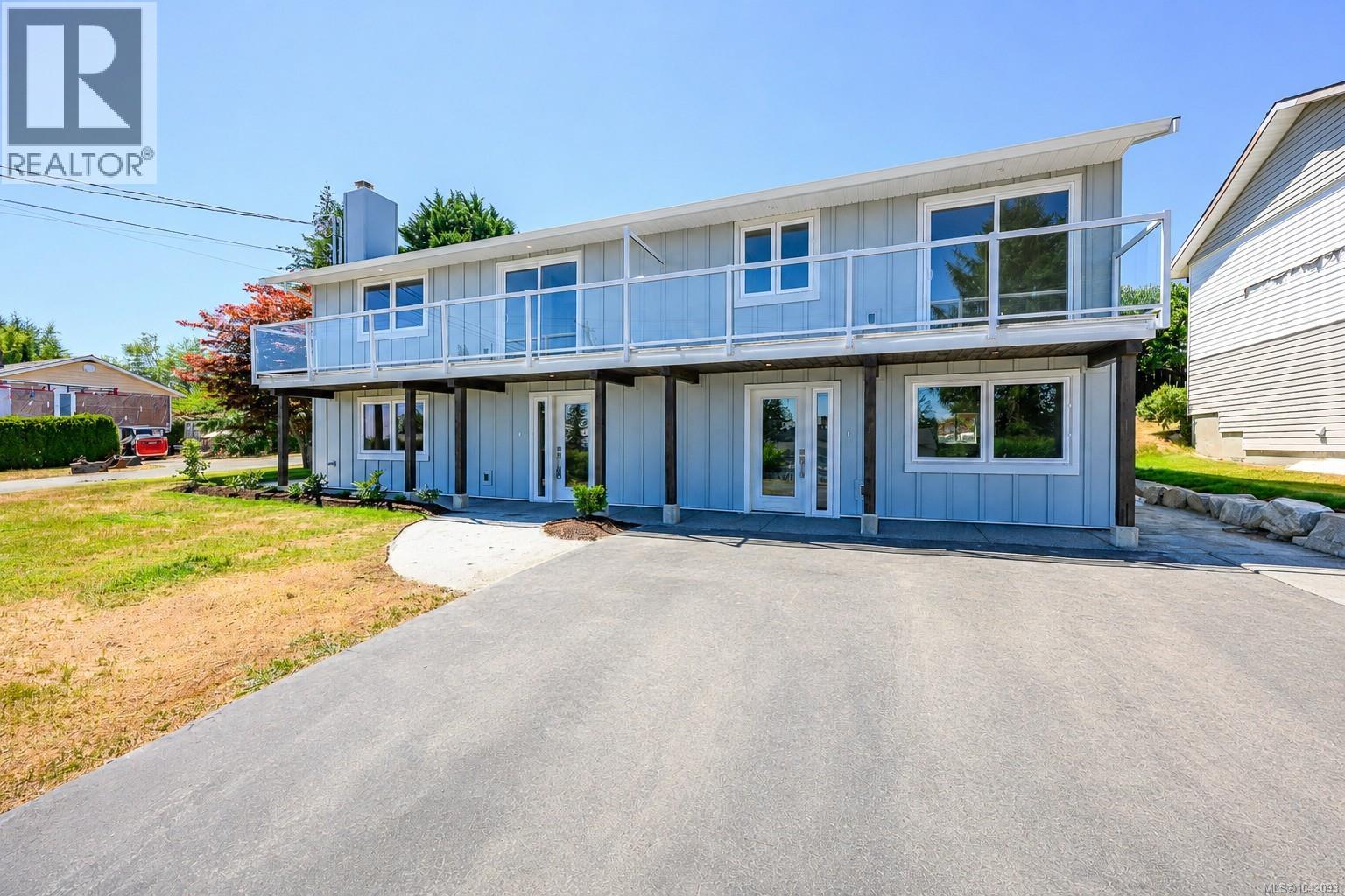 Contemporary two-story Side-by-side duplex exterior with light blue siding, a top-level balcony featuring glass railings, and multiple large windows