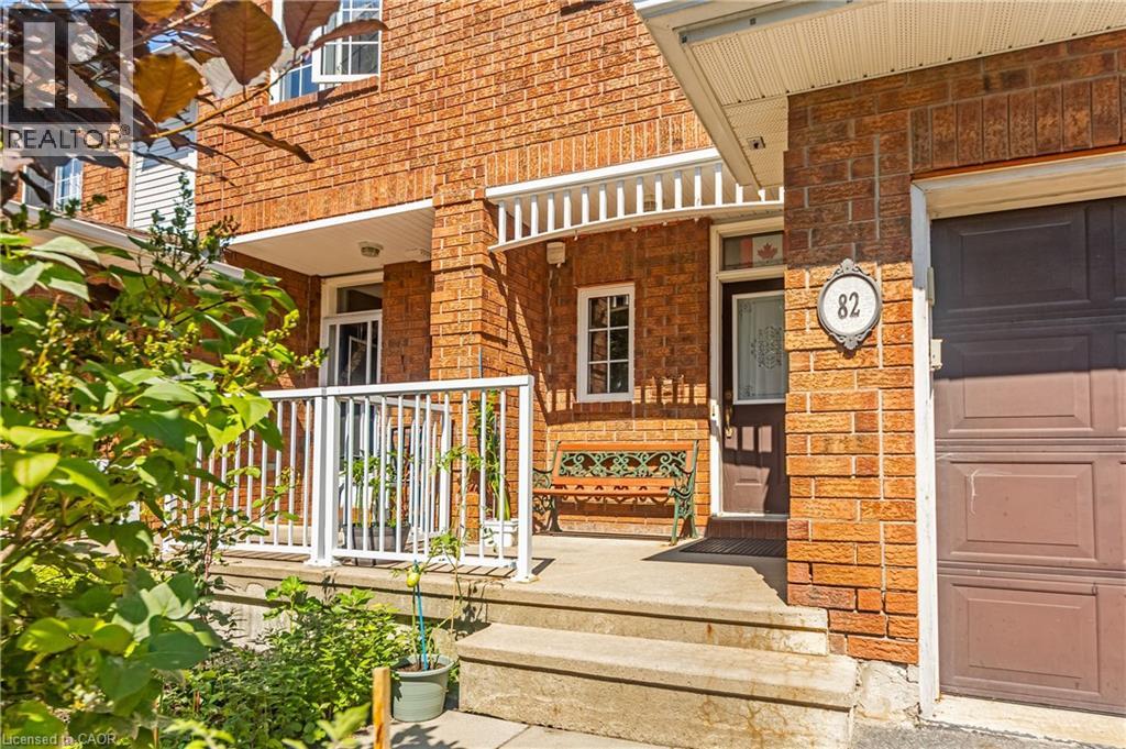 Brick exterior with a covered porch, white railing, concrete steps, and a dark wood entry door