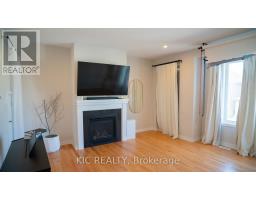 Fireplace with TV, oval mirror, and hardwood floors - 352 Appalachian Circle Ottawa