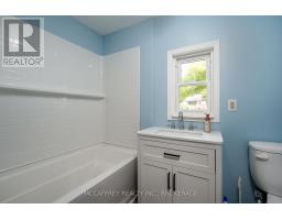 Bathtub, vanity, and toilet in a renovated bathroom with subway tile and blue walls - 2956 County Road 14 Stone Mills