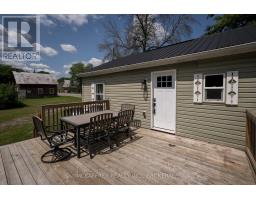 Deck with dining set, green siding, black roof, and old barn - 2956 County Road 14 Stone Mills