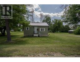 Green house with white trim windows and metal roof - 2956 County Road 14 Stone Mills