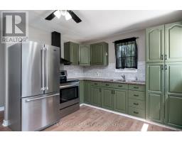 Kitchen with stainless steel appliances, green cabinets, and brick backsplash - 2956 County Road 14 Stone Mills
