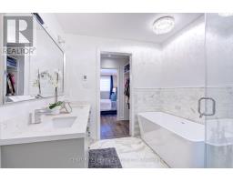 Freestanding bathtub and double vanity in renovated bathroom with walk-in closet view - 109 Woodcroft Lane Vaughan