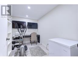 Elliptical machine, desk, and chest freezer in a room with two TVs - 109 Woodcroft Lane Vaughan