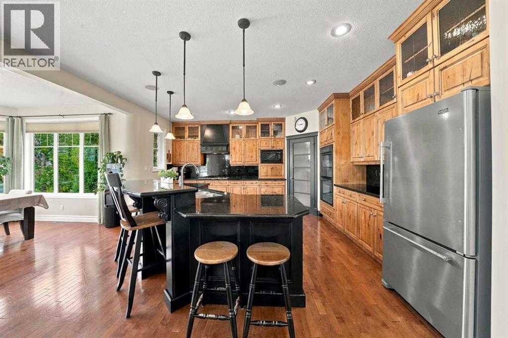 The kitchen offers an abundance of custom knotty alder cabinetry, granite countertops, a gas cooktop with a custom range hood, and a large walk-through pantry with a second fridge