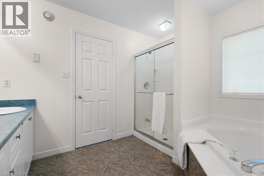 Shower enclosure with clear glass doors, white built-in tub, and a vanity with a blue countertop and white cabinetry