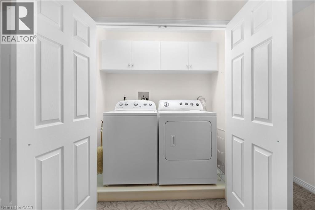 Dedicated laundry area featuring white paneled bi-fold doors, upper cabinetry, and a washer and dryer