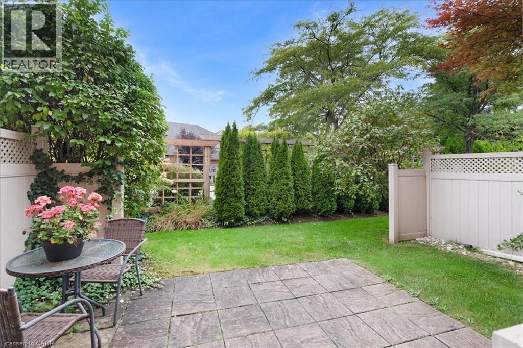 Stone-tiled patio with an expansive lawn, white lattice fencing, and mature landscaping