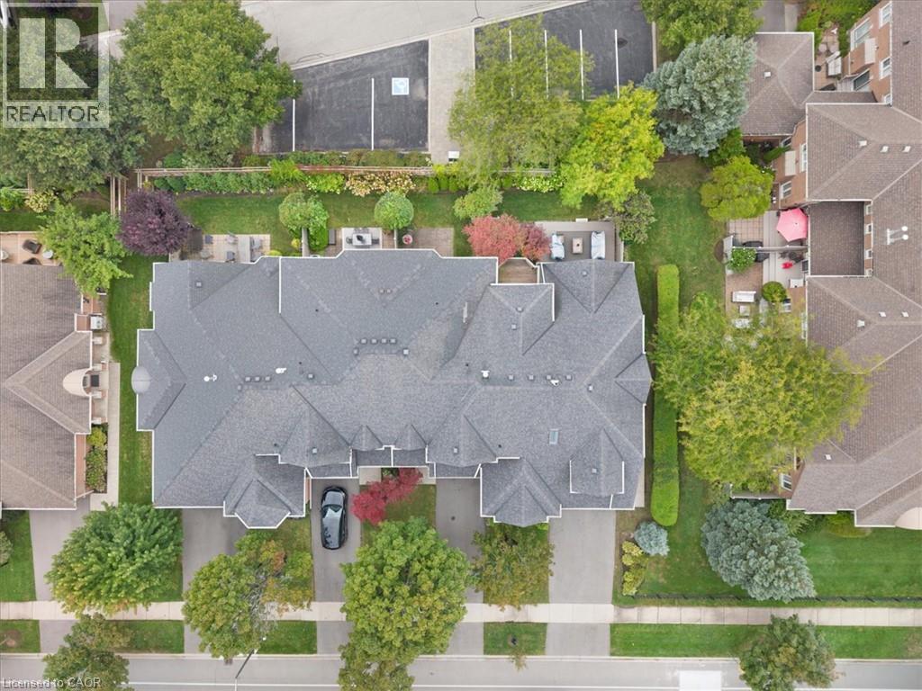 Shingle roofline, paved driveway, landscaped yard, concrete sidewalks, and mature trees