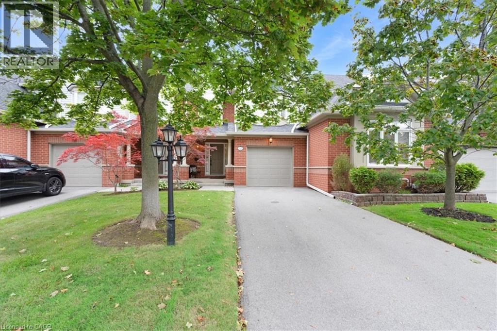 Brick facade, attached garage, paved driveway, mature trees, landscaped planting beds