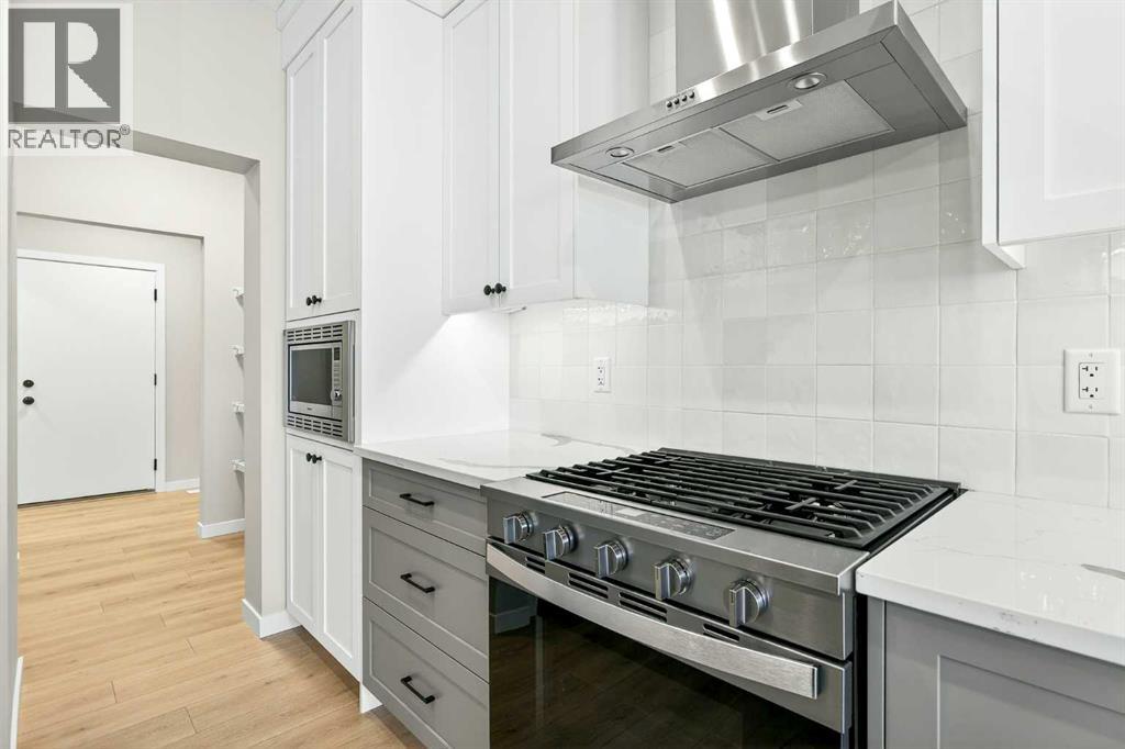 Gas range, tiled backsplash with chimney style hood fan