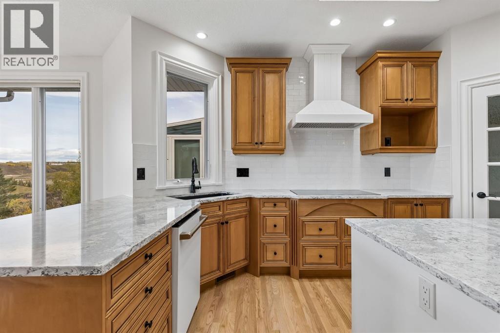 Bright finishes pair beautifully with warm wood cabinetry, quartz countertops, a tiled backsplash and sleek induction cooktop, creating a timeless and highly functional workspace