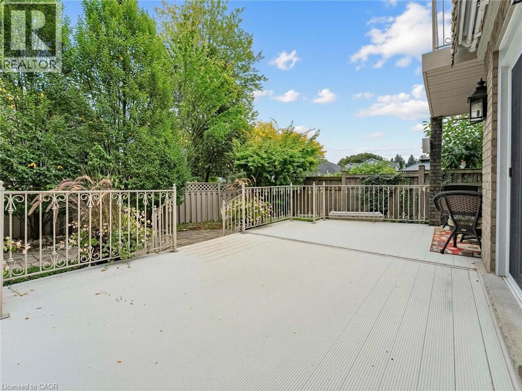 Expansive composite deck with ornamental metal railing, brick exterior, and attached outdoor lighting fixture