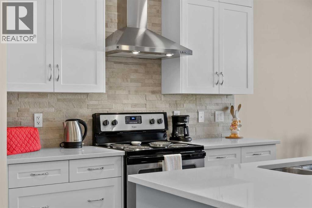 A stacked stone backsplash and stainless steel hood bring texture and warmth to the cooking area
