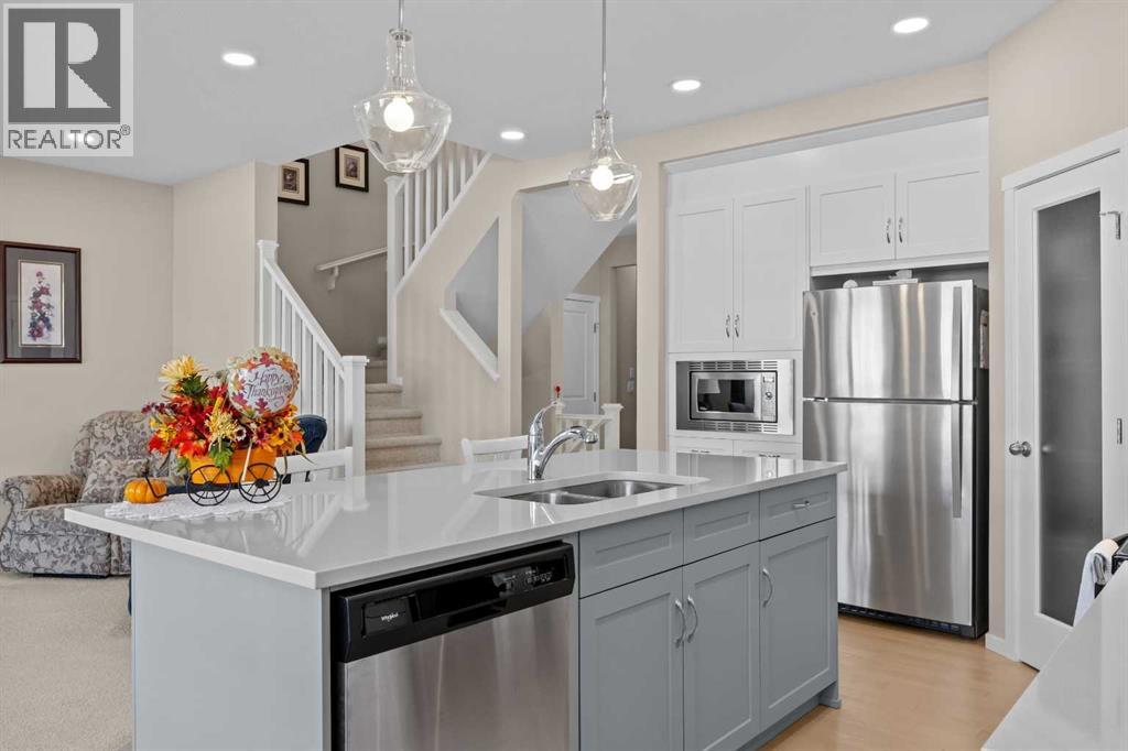 The kitchen sits at the heart of the main floor, with crisp white ceiling height cabinetry, quartz countertops, and stainless steel appliances