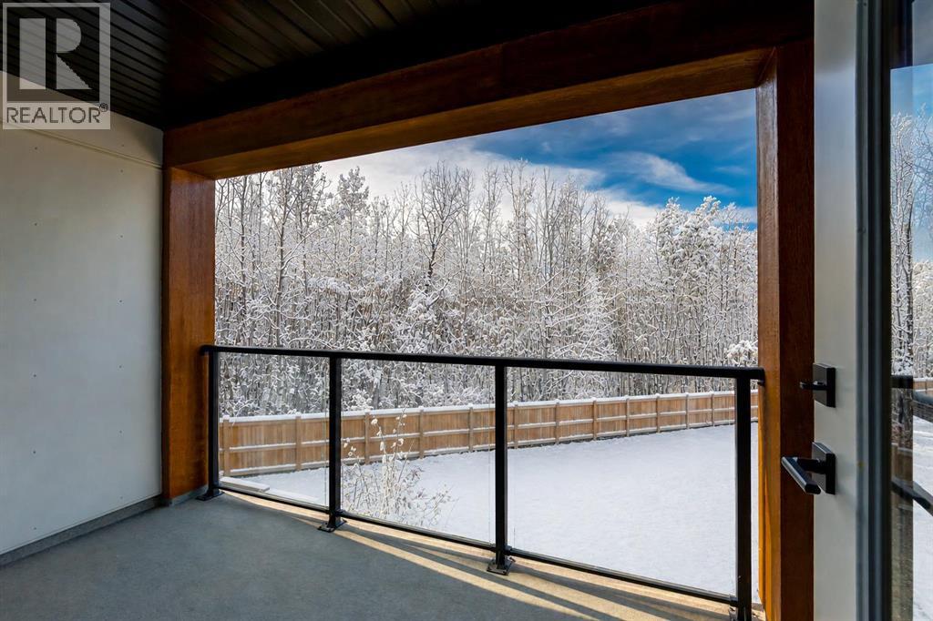 Private balcony off the primary suite with south exposure overlooking poplar treed wood