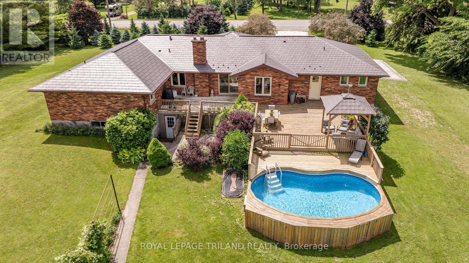 Welcome to the tranquility of the countryside on this stunning property only minutes from London, perfect for those seeking the comfort of nature, open green space and a touch of rustic luxury. Ensconced in 1000s of mature trees, this 17.9 acre estate offers a host of amenities to fulfill your dream of country living. Custom built beautifully maintained brick bungalow, a dreamworld of spacious rooms awaits. MAIN FLOOR: 4 bedrooms (primary with walk-in closet and ensuite), 3 bathrooms, open concept family room with fireplace, stunning wide kitchen and dining room, sunny front office, TV room, art room, laundry! The BASEMENT has potential as a separate living space with its separate entrance, bedroom 5, bathroom, kitchen, dining room, wet bar and games room, rec room/theatre room with second fireplace! OUTSIDE: enjoy activities year-round with 1 km of trails through your private forest, beautiful pond with its own island that becomes a skating winter wonderland, and a charming cabin in a clearing to toast marshmallows over your firepit! Love culinary adventures with your own dedicated smokehouse. Live off the land? There's a lush vegetable garden, grape vines, fruit orchard, approximately 1200 evergreen trees, and 5 acres of arable land for you to farm! A fully equipped 55X26 shop with hydro is ideal for hobbyists, woodworkers, and automotive enthusiasts. BBQ and enjoy dinner under the gazebo or in full sunshine on your huge deck and then take a dip in the kidney-shaped pool or watch the koi fish in the second pond. (id:48254)