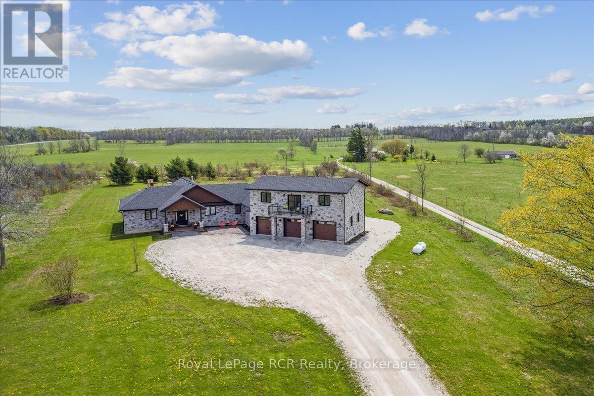 Welcome to a home that has it all, style, space, and seriously great vibes! This custom stone beauty offers 5 bedrooms, 4 bathrooms, and sits on just over 2 acres, giving you the perfect mix of peaceful country living and convenience, only 10 minutes to Owen Sound. Designed with flexibility in mind, it's ideal for a growing family or anyone looking for a multigenerational living setup. The in-law suite is a standout feature, completely separate and located above the triple car garage. It includes 2 bedrooms, a 3-piece bathroom, a full kitchen, and a bright living room with a walkout to a private balcony. Whether it's for parents, adult kids, or guests, this space offers both comfort and independence under one roof. The triple car garage is a dream on its own, with a drive-thru 4th door and heated floors. And speaking of heat, you'll enjoy in-floor heating and luxury vinyl flooring throughout the entire home, perfect for cozy, low-maintenance living. The main living area is open-concept and made for connection, with the kitchen, dining, and great room flowing seamlessly together. Vaulted ceilings with wood beams add charm to the great room and dining area, anchored by a floor-to-ceiling stone fireplace. The kitchen is both stylish and functional, featuring a large all-wood island, stunning live-edge quartz countertops paired with custom cabinetry, stainless steel appliances, and a spacious walk-in pantry. The primary suite is your personal retreat, complete with a spa-like 5-piece ensuite featuring a soaker tub and a generous walk-in closet. The additional bedrooms are bright, comfortable, and offer plenty of space for family, guests, or a home office, each finished with the same beautiful attention to detail and quality found throughout the home. If you're looking for space to grow, room to breathe, and a home that fits your lifestyle, this is the one! (id:48254)