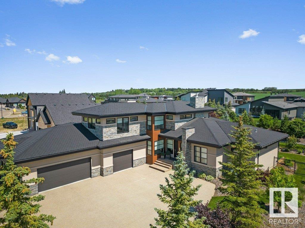 MOSAIC CRAFTED - LUXURIOUS EXECUTIVE BUNGALOW in prestigious Rivers Gate features over 5400 sqft of DESIGN EXCELLENCE. The open-concept design features soaring 20' ceilings, custom millwork, sun-drenched great room with floor-to-ceiling windows & feature gas fireplace. The chef’s kitchen offers quartz counters, professional series stainless steel appliances, custom cabinetry & a walk-through pantry. The primary suite is pure luxury, with a spa-like ensuite featuring a soaker tub, dual vanities, an expansive walk-in shower & custom closet. A second bedroom with a 4-pc ensuite, laundry, mudroom and executive loft complete the main. The finished basement offers 2 bedrooms, Jack-and-Jill bath, gym, huge family room with wet bar, 2-pc bath & ample storage. Radiant in-floor heating ensures year-round comfort. Spectacular landscaping, tiered patios & the enclosed lounging deck complement the oversized quad garage with EV charger & workshop. Unparalleled elegance conveniently located between St Albert & Edmonton (id:48254)