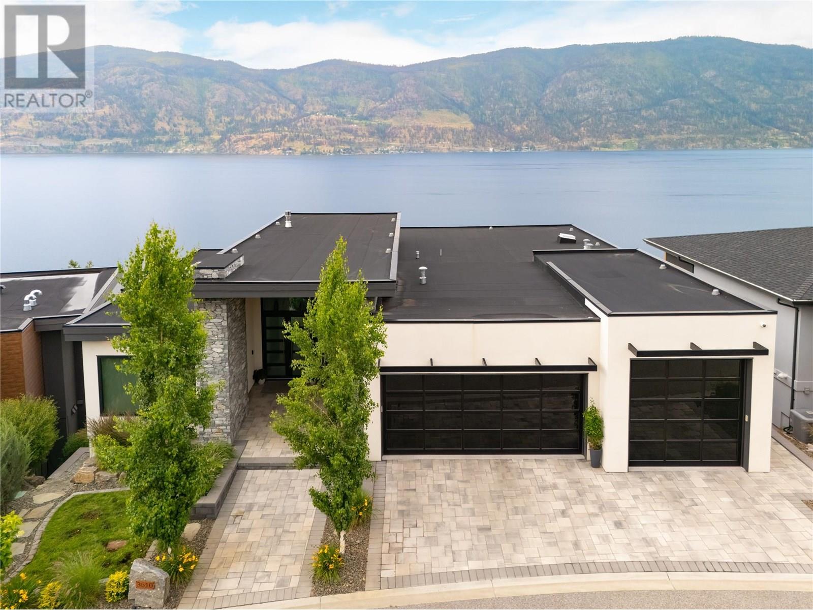 3610 Boxwood Road Kelowna, British Columbia This exceptional 5000+ SF home in McKinley Beach sits on a quiet cul-de-sac, just a short walk to the beach and marina. Enjoy stunning lake views from both levels, an oversized 3.5-car garage, and a 16-foot long, 5 foot deep, swim spa. The main level features a rare and desirable layout with the primary suite plus two additional bedrooms all on one floor. The primary offers lake views, a fireplace, and a spa-like ensuite with walk-in shower, soaker tub, heated floors, and double vanity. The kitchen is outfitted with Fisher & Paykel paneled appliances and a pass-through window to the outdoor dining area. Wood beams and a gas fireplace bring warmth and character to the living room with soaring ceilings. Downstairs includes two more bedrooms, a full bath, a flex space with separate entry, and a spacious 2-bedroom legal suite. Movie nights shine in the state-of-the-art theater room with wet bar, starlight ceiling, and extra sound insulation. Other highlights: climate-controlled wine room, triple-pane windows, built-in speakers, Control4 system, security, power shades, and a gas firepit. Enjoy McKinley’s new amenity center with a gym, pool, hot tub, yoga room, and tennis/pickleball courts. (id:48254)