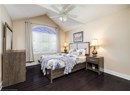 Bedroom featuring dark wood-type flooring, vaulted ceiling, a ceiling fan, and a textured ceiling