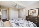 Bedroom with a closet, wood finished floors, ceiling fan, and ensuite bathroom