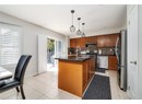 Kitchen featuring stainless steel appliances, brown cabinets, backsplash, light tile patterned floors, and a kitchen island with sink