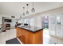 Kitchen featuring light tile patterned floors, dark stone counters, open floor plan, pendant lighting, and a center island with sink