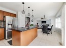 Kitchen featuring stainless steel fridge, light tile patterned floors, brown cabinetry, and tasteful backsplash