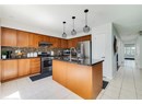 Kitchen featuring light tile patterned floors, appliances with stainless steel finishes, tasteful backsplash, dark stone counters, and an island with sink