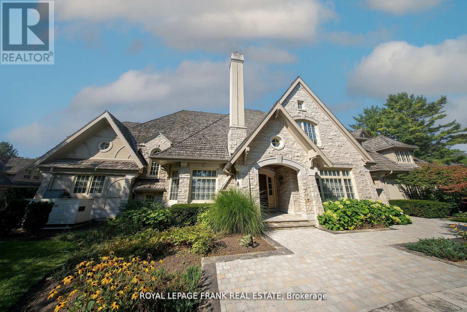 Situated in one of the most prestigious neighbourhoods, Deer Creek, 42 Buggey Lane is a true custom-built luxury estate spanning 1.42 acres with mature trees offering ultimate privacy and an English garden ambiance. Just steps from Deer Creek Golf Course, this 5000+ sq. ft. home features a timeless exterior blend of English Tudor Country with Gothic roofline peaks, crafted with Wiarton ledger rock, Indiana limestone, and Douglas Fir trim. Built in 2000, this residence was among the first smart homes, equipped with automated Hunter Douglas blinds and integrated smart home controls. Inside, the kitchen boasts Giallo Vittoria granite countertops with views overlooking the lush back garden. The Great Room, anchored by a dual Travertino Classico fireplace, is perfect for elegant gatherings. Hardwood floors throughout the main and upper level and a grand dining room to elevate luxury. The finished basement includes an additional bedroom, additional storage and a massive bunker. **EXTRAS** 4+1 bedrooms with primary and secondary bedroom on the main floor, offering comfort and accessibility. Upstairs has 2 additional bedrooms complete with a kitchen and living space and an oversized office. Ample parking with 4 car garage. (id:48254)