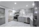 Kitchen with under cabinet range hood, gray cabinets, marble finish floor, stainless steel appliances, and a sink