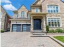 View of front facade featuring stone siding, an attached garage, decorative driveway, and stucco siding