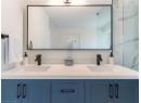 Full bath featuring double vanity and a marble finish shower