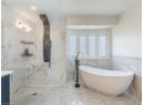 Full bathroom with tile walls, a freestanding tub, vanity, and a marble finish shower