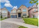 View of front of property with stone siding, decorative driveway, a garage, and a front yard